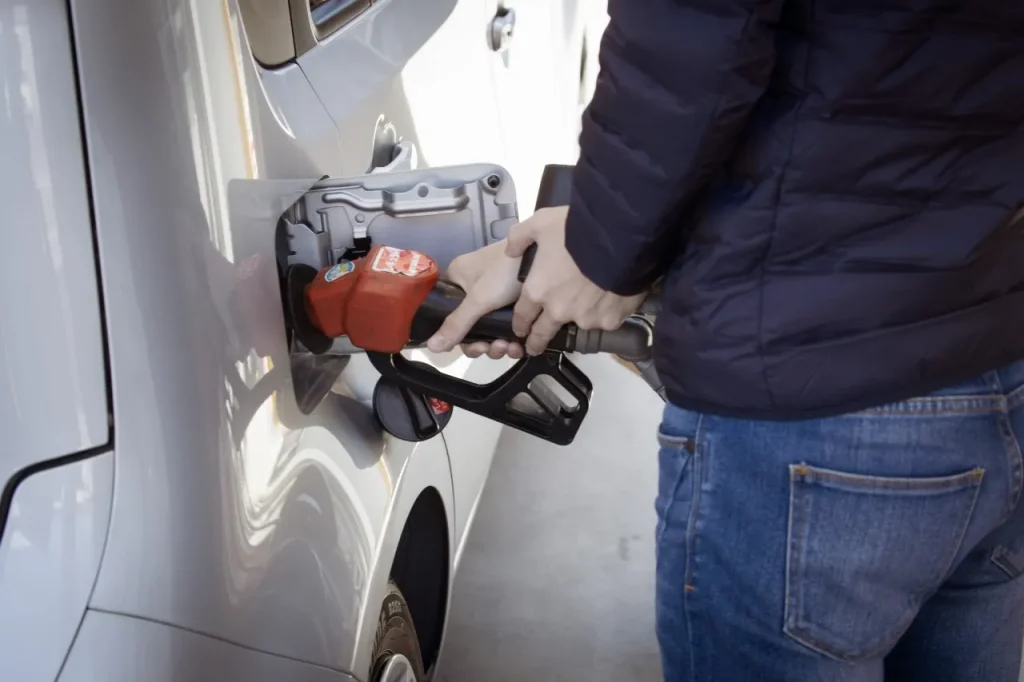 Petrol prices on the rise - person filling up a silver car at the petrol pump